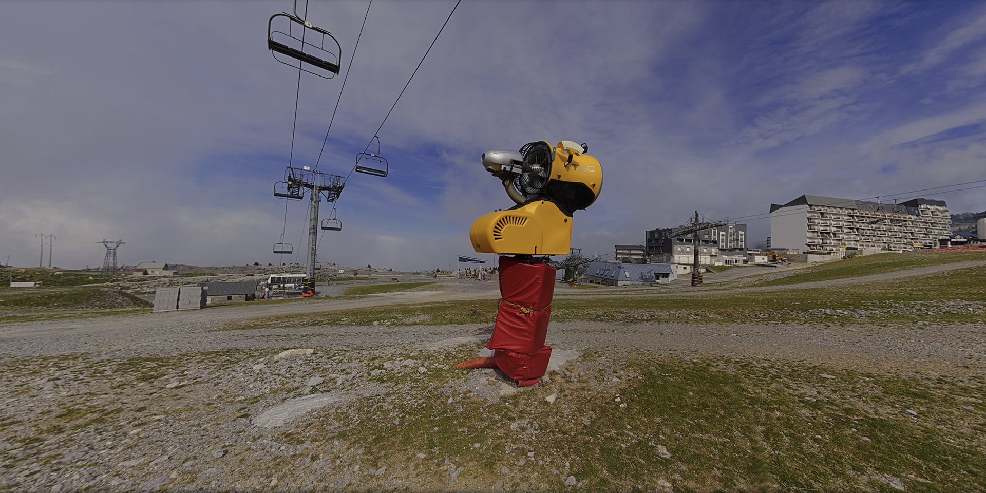 Canon à neige installé sur une piste de montagne enneigée, dans une visite virtuelle sur le tourisme hivernal et le climat